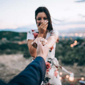 一位女性在黃昏時分的浪漫求婚中看到訂婚戒指時欣喜若狂。