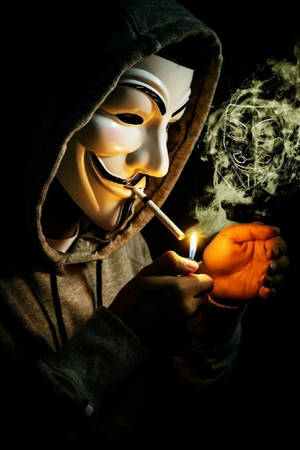 戴蓋伊·福克斯面具的人用打火機點煙，煙霧形成面具。 — 鬼滅之刃面具 壁紙