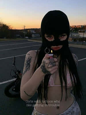 紋身女子戴黑色巴拉克拉法帽在日落時分停車場拿著點燃的打火機。