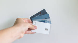 手持多張信用卡，包括Apple Card、Capital One和American Express。