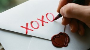手喺有心形蠟封嘅信封上寫xoxo。