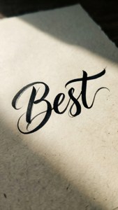 「Best」呢個詞以流暢嘅黑色書法字體寫喺有紋理嘅奶油色紙上面。 — iPhone 7 Plus 壁紙