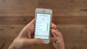 手持iPhone在木質表面上顯示Touch ID密碼設定。 — 手機鎖定螢幕 壁紙