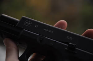 手持黑色 Glock 17 手槍，帶有「Austria」和「9x19」標記。