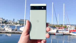 在碼頭拿著綠色 Google Pixel 手機，背景有船隻和城市建築。