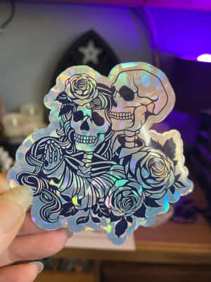 手在紫色光下拿著骷髏頭和玫瑰全息貼紙。