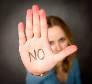 女人將手掌上寫有「NO」的手向前伸出，以示拒絕。