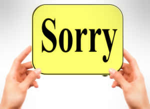 兩隻手拿著一個寫著 Sorry 的黃色牌子