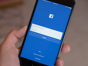 手拿著顯示Facebook登入頁面的手機