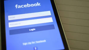智能手機在橫線筆記本表面上顯示Facebook登入畫面。