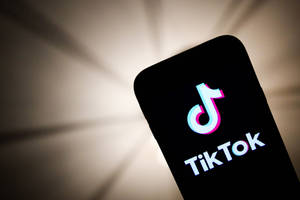 手機特寫，顯示TikTok應用程式標誌，背後有柔和光線。