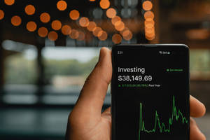 手拿著手機顯示投資組合，帶有綠色圖表和 $38,149.69 餘額。