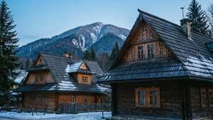 兩間被雪覆蓋的木屋，背景是雪山。