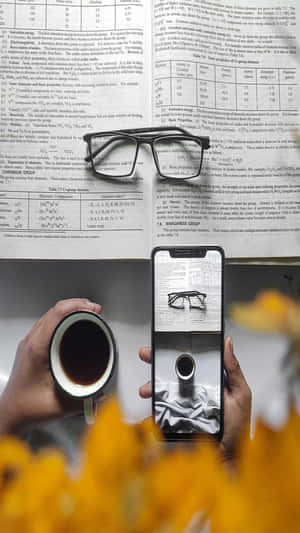 手拿著手機，顯示眼鏡在化學教科書上方，同一副眼鏡放在上面。