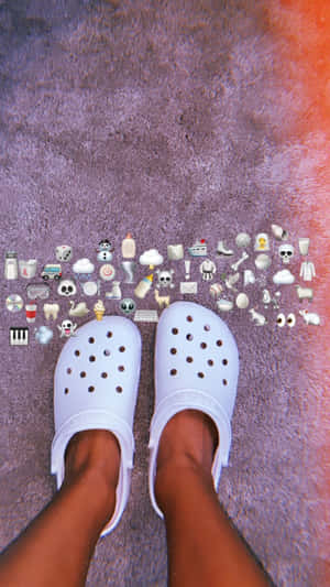 紫色地毯上的白色Crocs，周圍有表情符號貼紙。