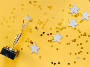 金色獎盃 surrounded by stars and confetti on yellow background — 勝利 壁紙