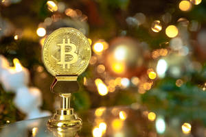 金色比特幣獎盃在反光表面上，背景是模糊的聖誕燈飾。