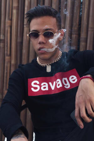 年輕男子戴太陽眼鏡和 'Savage' 連帽衫在竹牆附近吸煙。