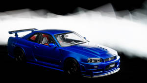藍色日產Skyline GT-R模型車，配有紅色座椅和黑色車輪，在煙霧繚繞的攝影棚燈光下。 — 藍色 壁紙