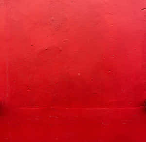 帶有紋理的紅色油漆牆面特寫，包含輕微瑕疵。 — 紅色 壁紙