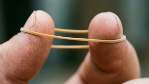 兩隻手指將一條米色橡筋拉緊。
