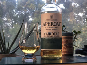 一瓶Laphroaig威士忌和品酒杯放在有植物的窗台上。