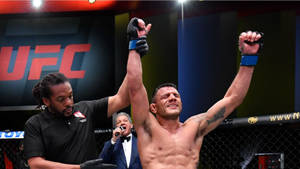 UFC拳手在八角籠中舉臂慶祝勝利。