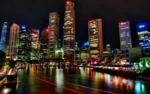夜間城市景觀，有燈火通明的摩天大樓和河上的光跡。