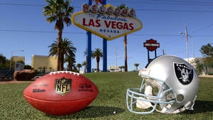 拉斯維加斯歡迎標誌前的NFL足球和Raiders頭盔。