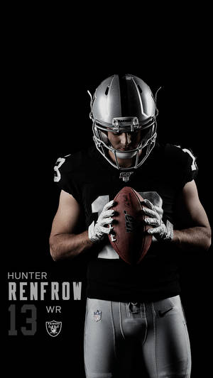 美式足球員 Hunter Renfrow 身穿 Raiders 裝備，抱著一個足球。