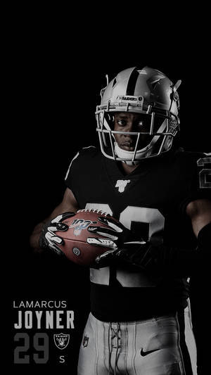 足球運動員Lamarcus Joyner身穿Raiders制服在攝影棚拍攝中持球。