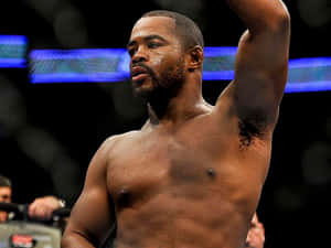 一位赤裸上身的MMA鬥士在明亮的八角籠中勝利地舉起手臂。