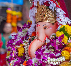 一個色彩繽紛的象神雕像，裝飾著花朵和金色皇冠。