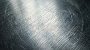 拉絲金屬表面的特寫，帶有對角線刮痕和柔和漸變照明