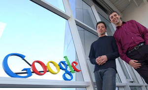 兩名男子在玻璃建築的Google標誌旁擺姿勢。