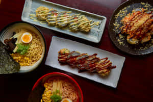 深色木桌上擺放的各式日本料理，如拉麵和天婦羅。 — 美食 壁紙