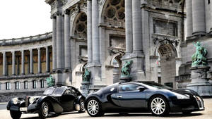 兩輛Bugatti汽車停在一座帶有雕像的宏偉石建築前。