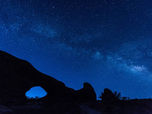 在繁星點點的夜空下，岩石拱門的剪影，銀河系清晰可見。