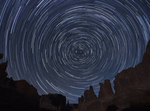 星軌在深藍色夜空下盤旋於沙漠岩石地貌之上。