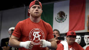 Canelo Alvarez身穿紅色拳擊裝備和白色護手繃帶，站在身後有墨西哥國旗的健身室內。