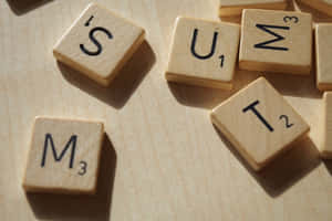 木質表面上拼出 SUM 和 IS 的 Scrabble 遊戲字母牌。 — MacBook 壁紙