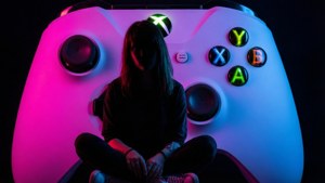 人坐在一個巨大的發光Xbox控制器內，帶有霓虹粉紅色和藍色燈光。