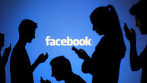 剪影人物在藍色 Facebook 標誌前使用手機。