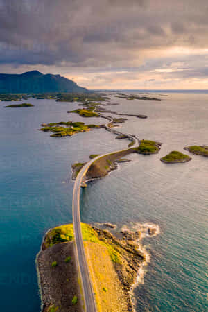 一條蜿蜒的海岸公路在日落時分以戲劇性的雲彩連接島嶼。