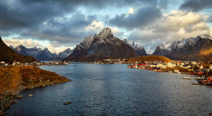 峽灣中的沿海村莊，黃昏時被積雪覆蓋的山脈環繞。