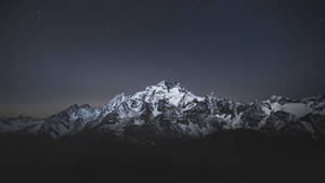 繁星夜空下帶有微弱極光的積雪山脈