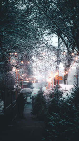 夜晚在燈串下撐傘在雪中行走的人