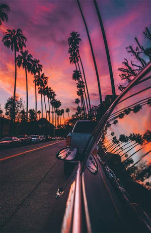 汽車在色彩繽紛的夕陽天空下駛過棕櫚樹。