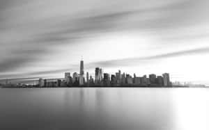 黑白城市景觀，摩天大樓和移動的雲朵倒映在水中。