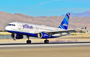 JetBlue 飛機在跑道上，背景有沙漠山脈